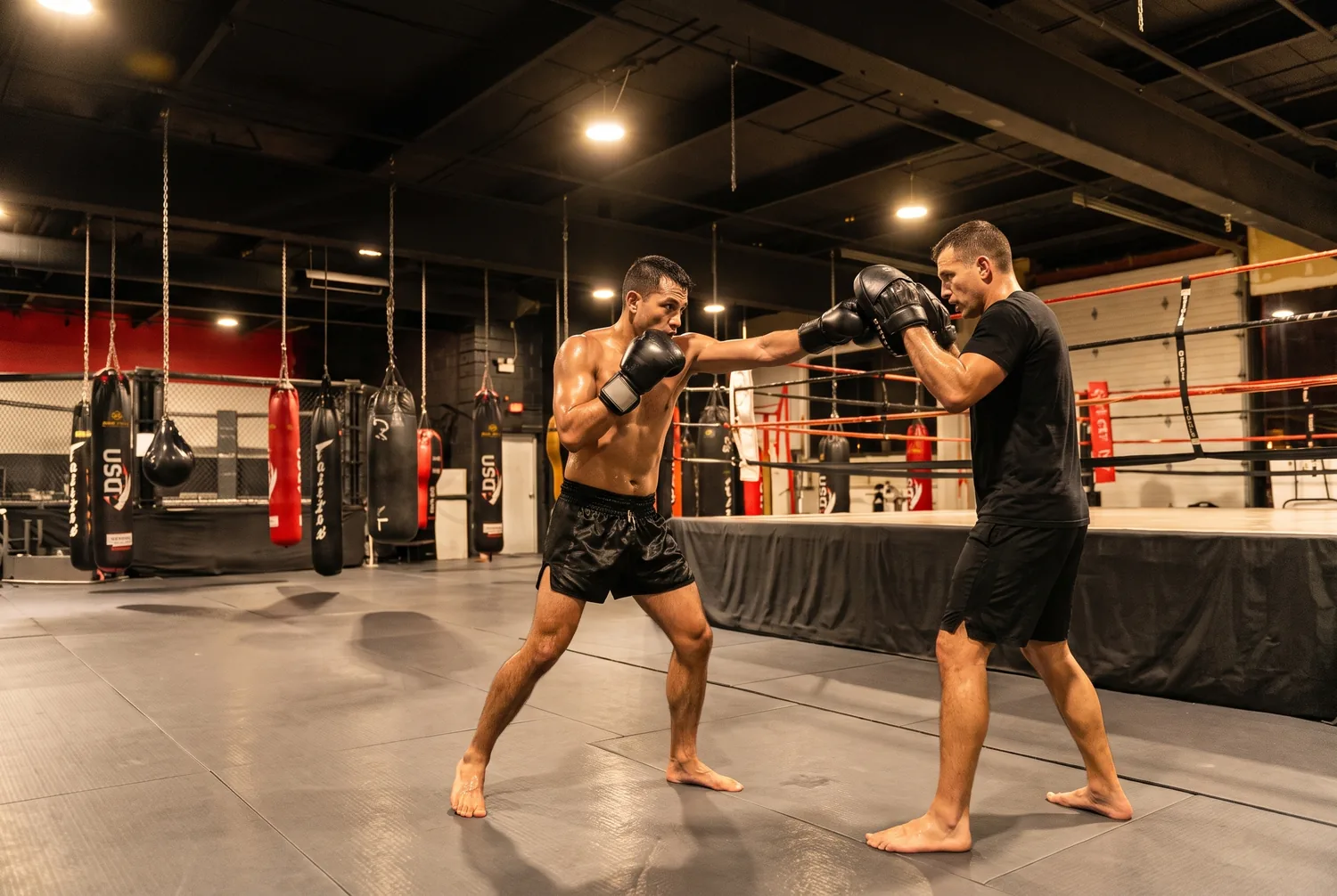 An adult Muay Thai student throwing a jab-cross combination on focus mitts at Xtreme Couture